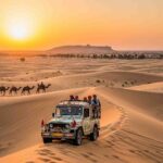 A jeep and camel caravan on golden sand dunes at sunset in the Thar Desert, Rajasthan