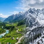 Panoramic view of lush green valleys and snow-capped mountains in Himachal Pradesh, representing the best season to visit Himachal.