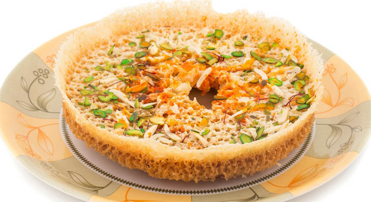 Disc-shaped honeycomb Ghevar topped with rabri and saffron, a famous Rajasthani festival sweet from Jaipur